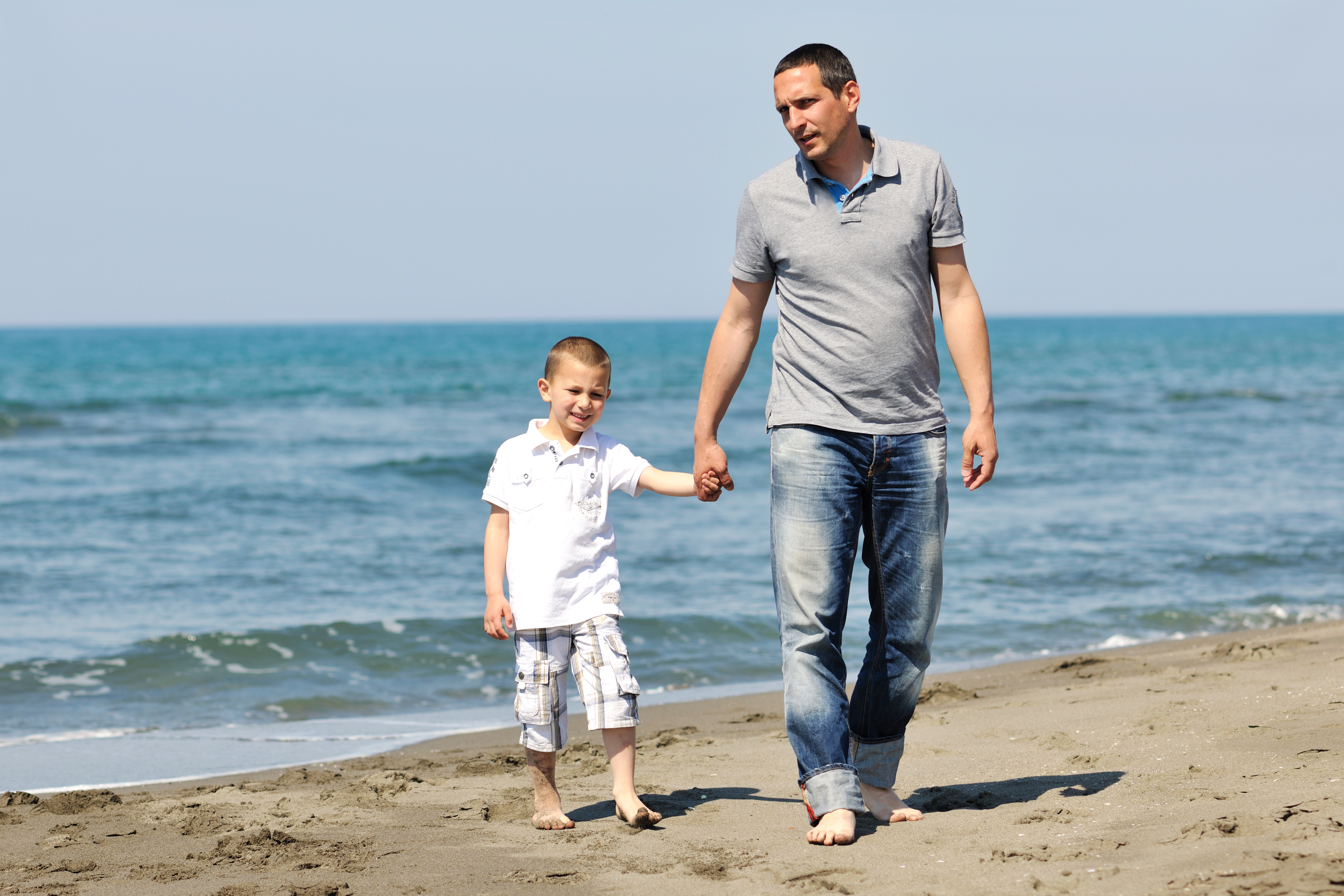 father and son walking at beach front